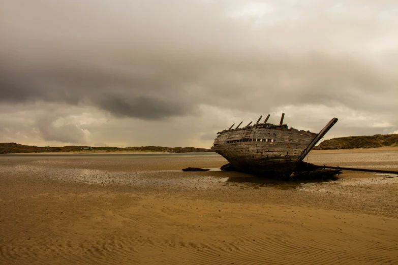 the wooden boat is sitting on top of the sandy beach