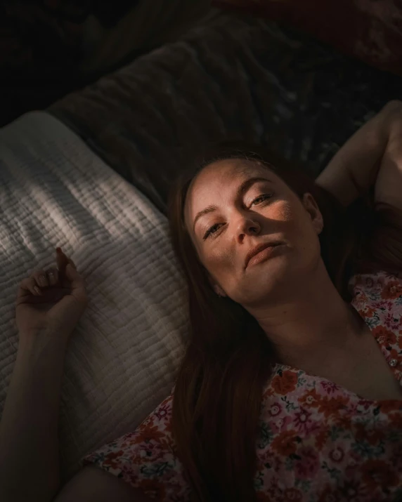 a young lady laying on a bed with her head on the pillow