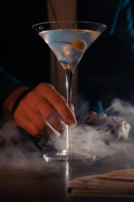 a person holding onto a glass filled with liquid