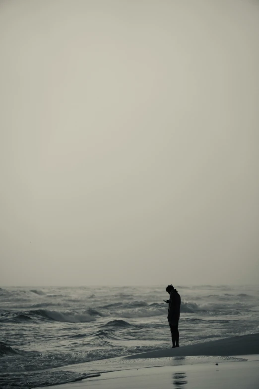 a person is standing on the beach while watching the ocean