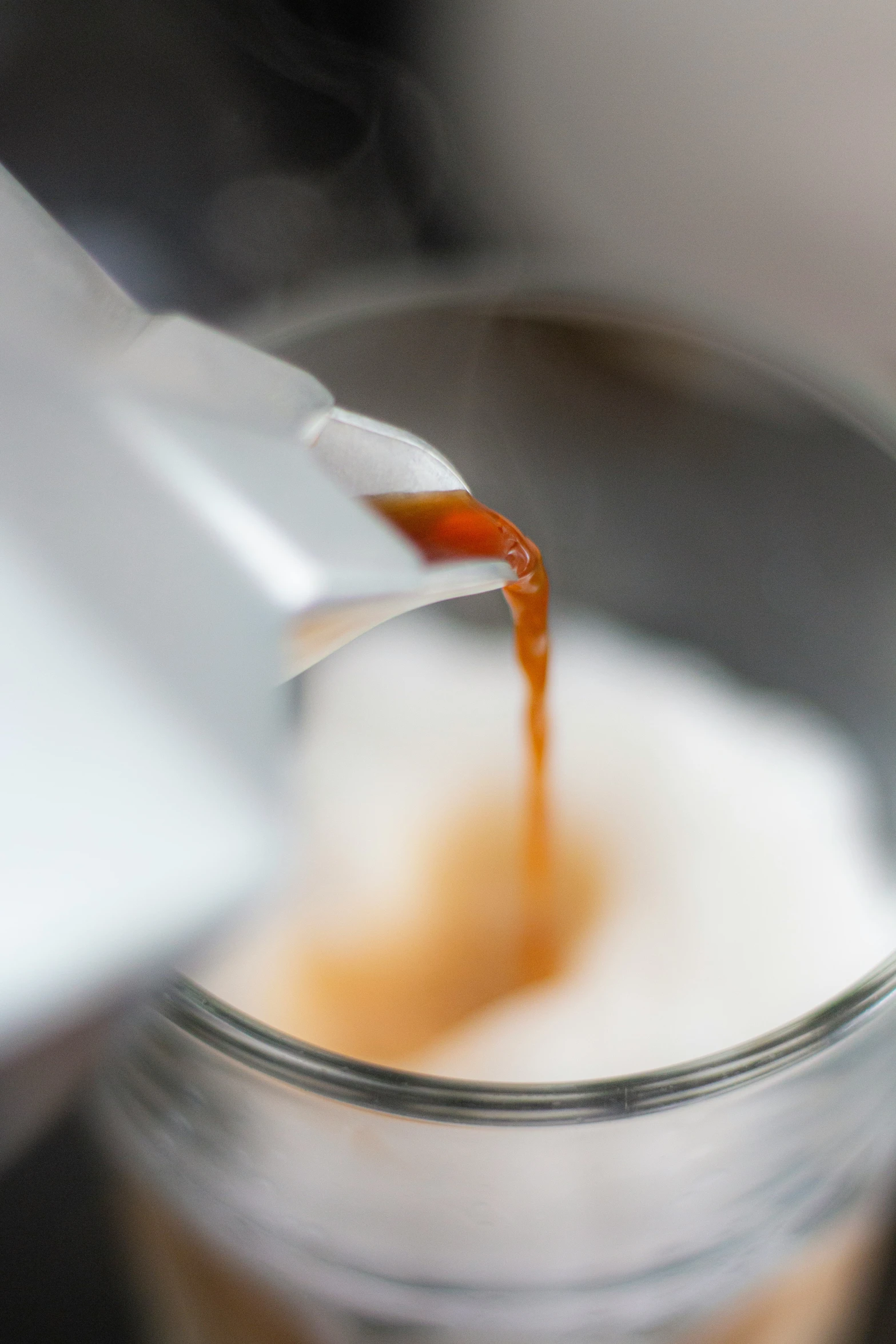 someone holding onto a spoon over a bowl with some liquid