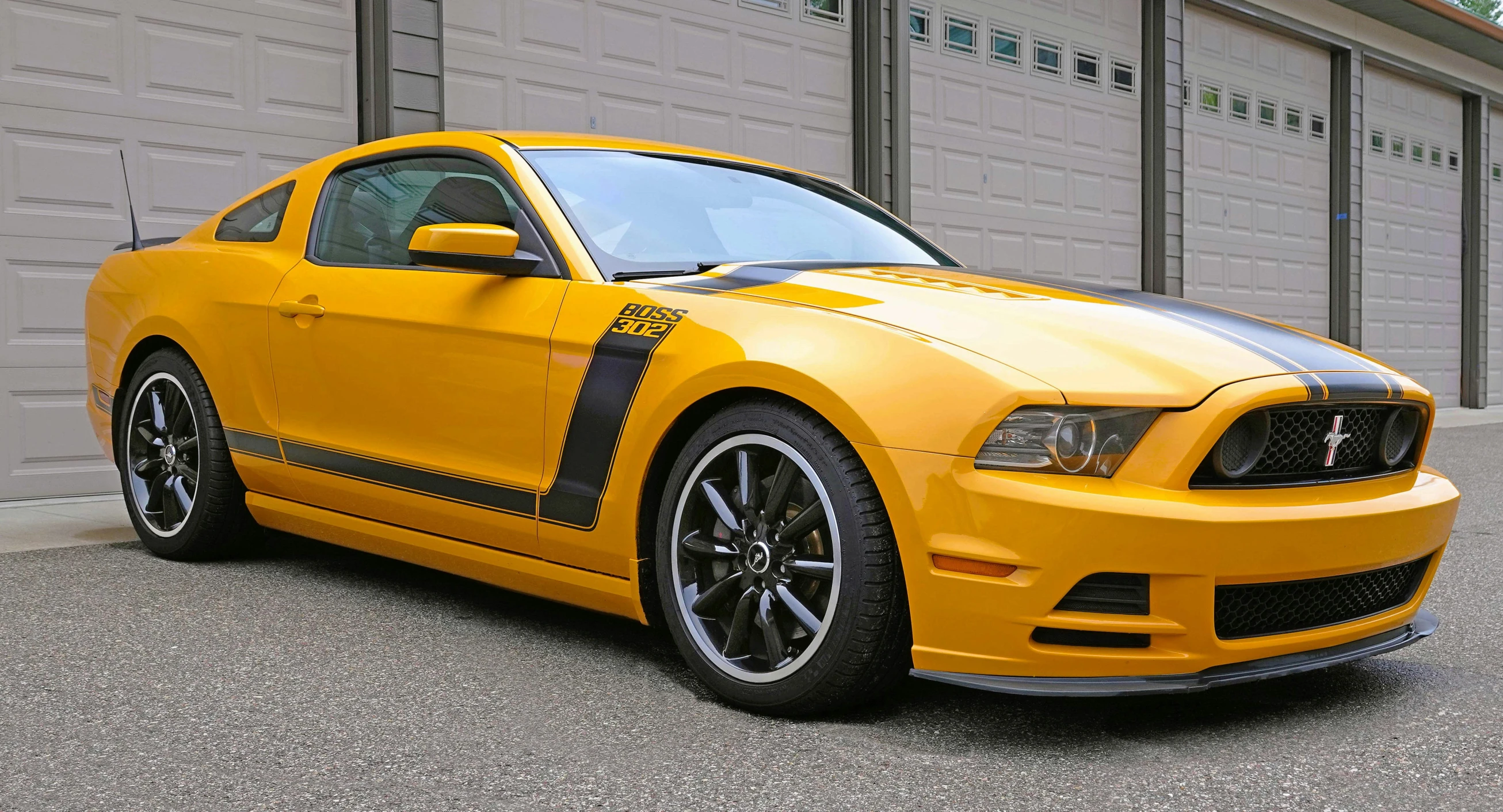 a yellow mustang is parked in front of a garage