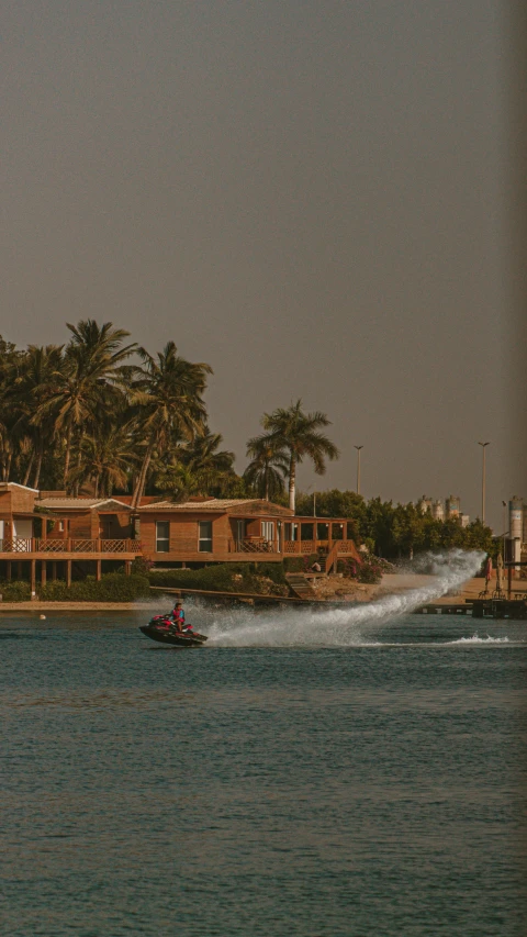 a boat speeding through the water with palm trees in the background