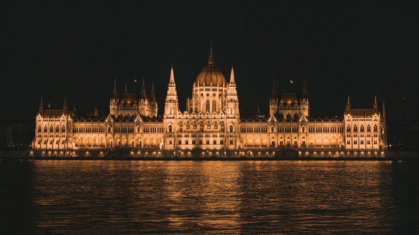 a large old city building in front of a body of water