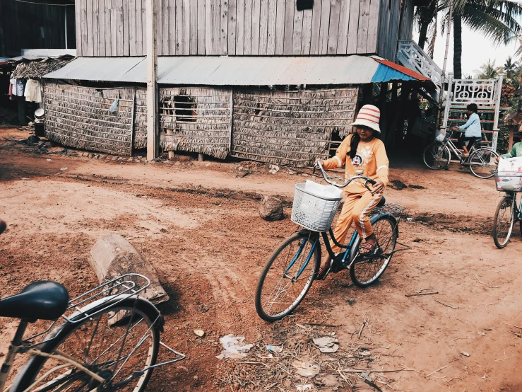 a woman sitting on top of a bike in front of a wooden building