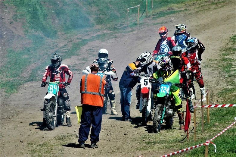 several motorcyclists are standing around in the dirt