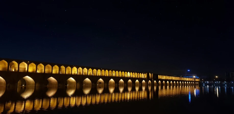 a large building lit up in the night with water around it