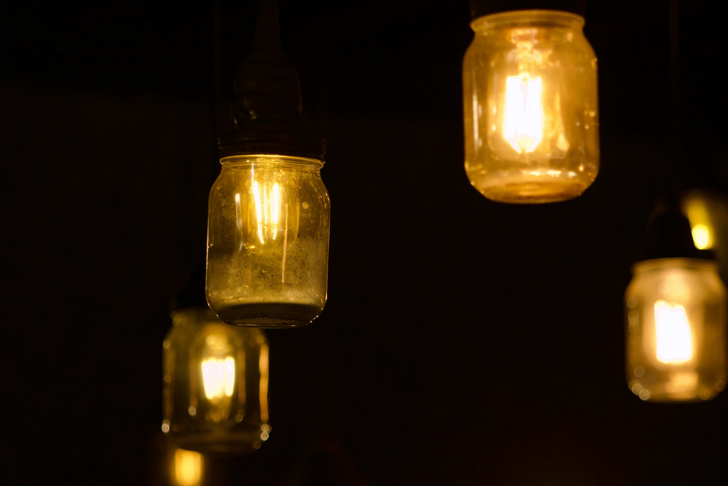 glowing mason jars of lights hanging in the night