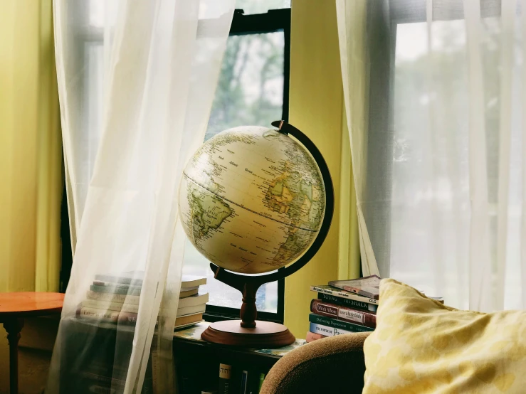 a globe in a room with a curtain and some books