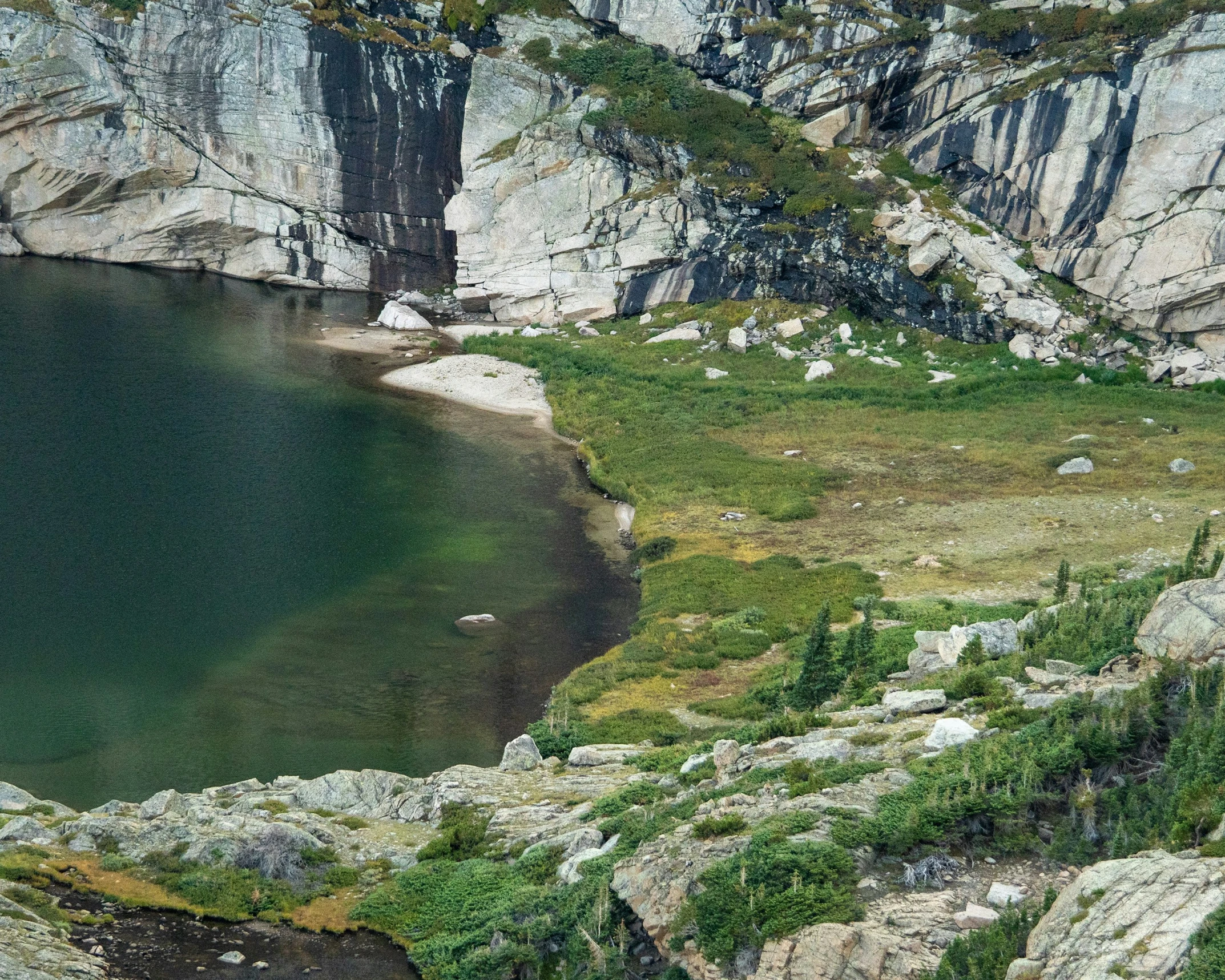 a large body of water sitting under a mountain side