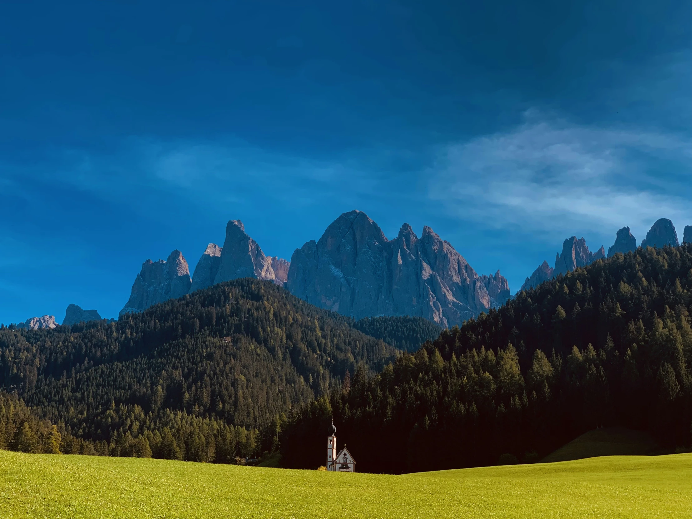 the green countryside is surrounded by mountain peaks