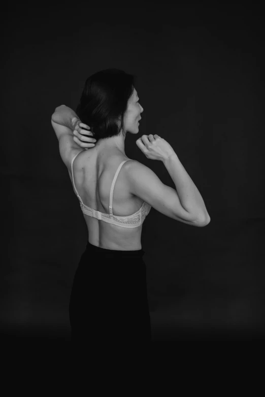 a black and white image of a woman holding her back