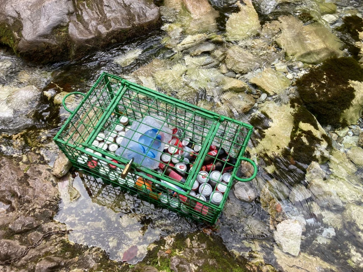 a green basket filled with plastic toys sitting on top of a rocky cliff