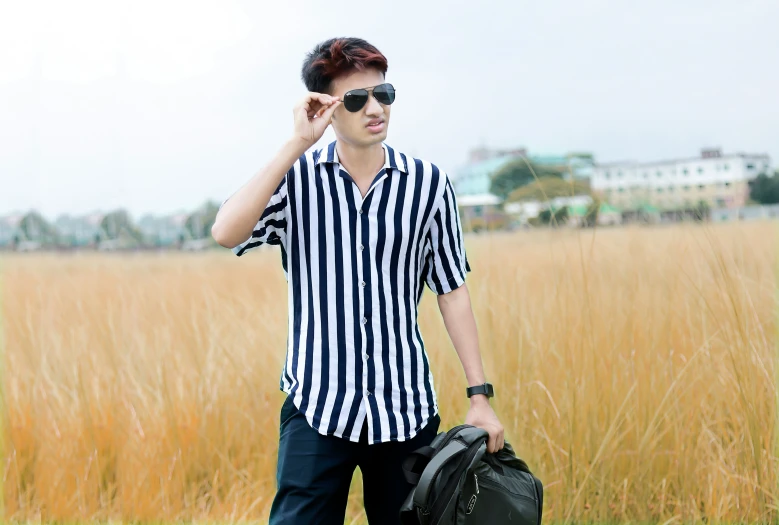 a young man with glasses holds a suitcase