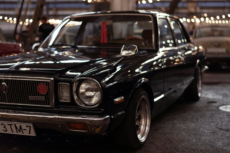 a black vintage car parked in the garage with christmas lights