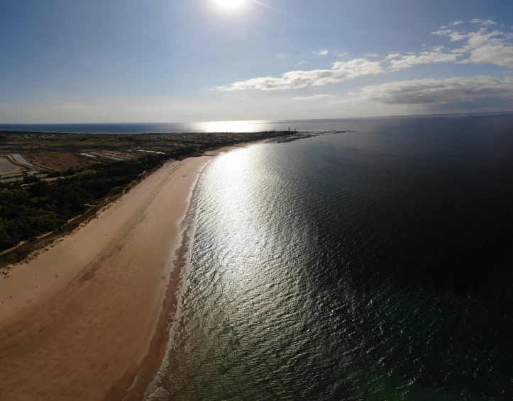 the sun shines over the beach in front of a clear blue ocean