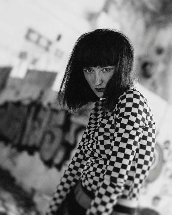 a woman wearing checkered shirt standing in front of wall