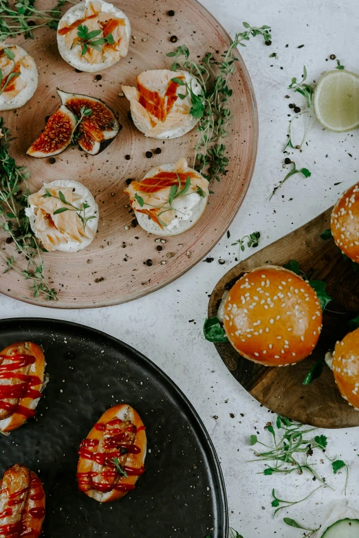 trays of deviled eggs covered with bacon and sprouts, next to two different types of other foods