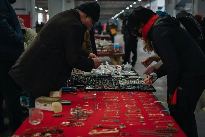 a person bending over to examine jewels at an outdoor flea market