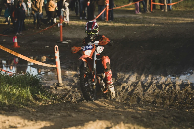 a motor bike races on a muddy course with a number of spectators