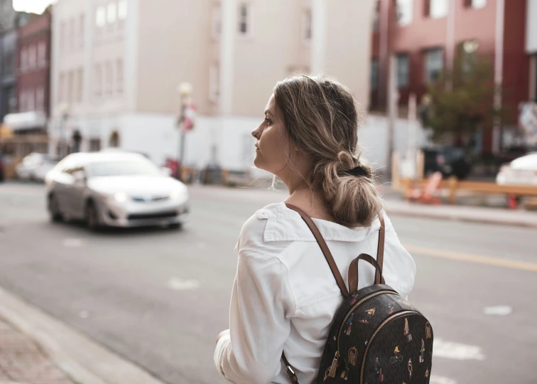 a woman is standing on a sidewalk near a busy street