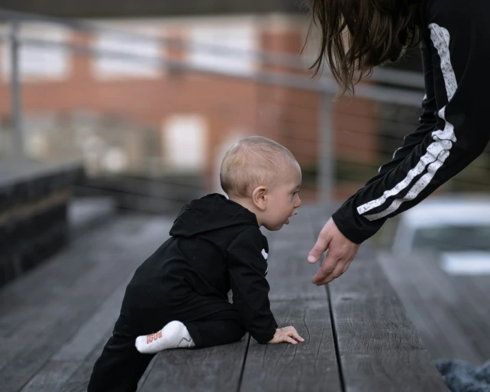 a toddler on a wooden surface next to an adult