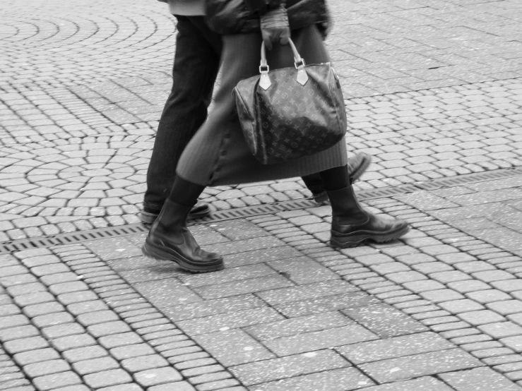 two people walking down the sidewalk while carrying their bags