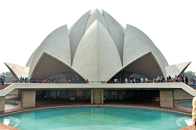 people in a large building stand on a concrete platform above the water