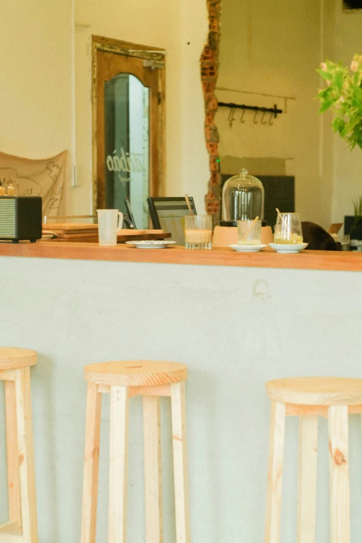 three wooden bar stools and a vase with flowers