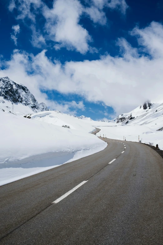 the road is surrounded by snow and mountains