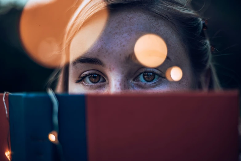 the eyes of a  peering over a red book