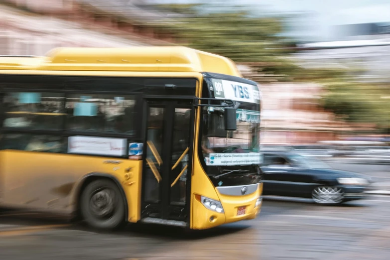 a yellow bus going down the street in motion