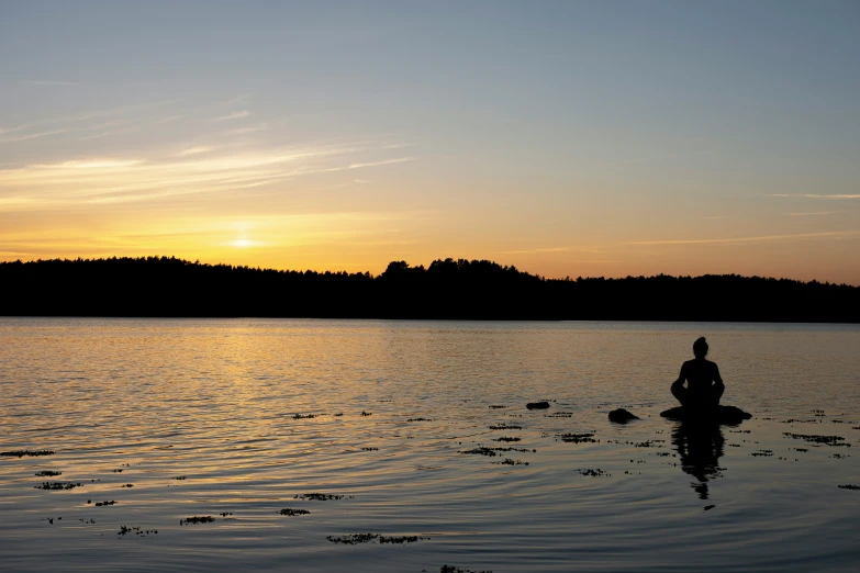 a person is fishing at sunset with the sun setting