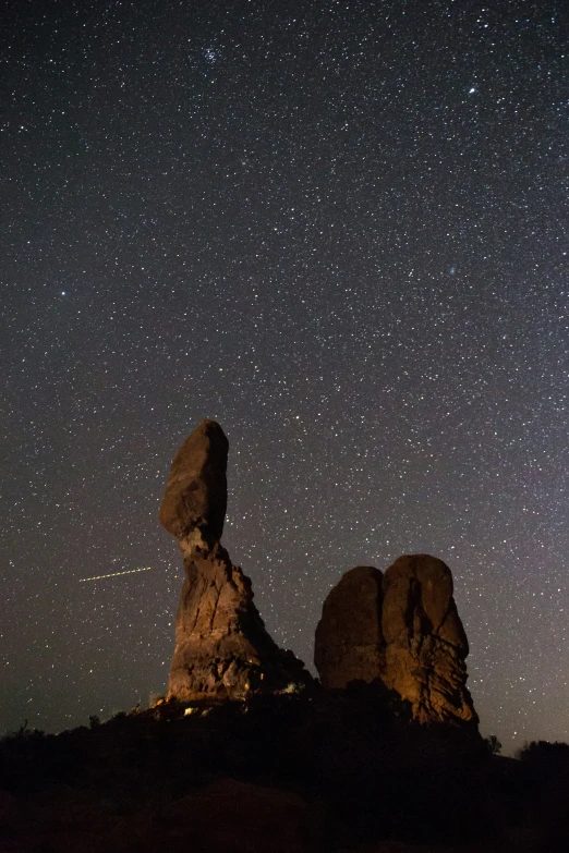 stars are shown in the sky above some large rocks