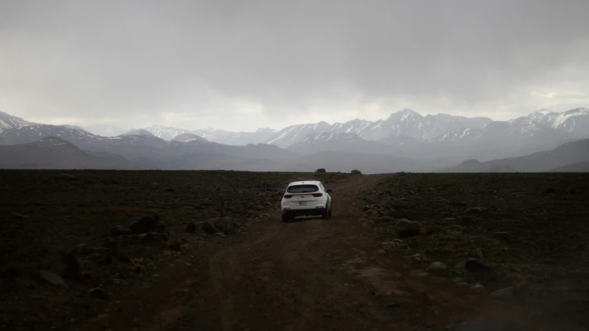 an suv in a field with mountains behind it