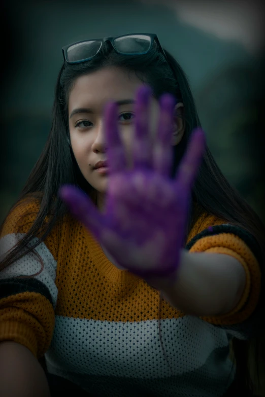 a woman in yellow and black shirt holding her hand up