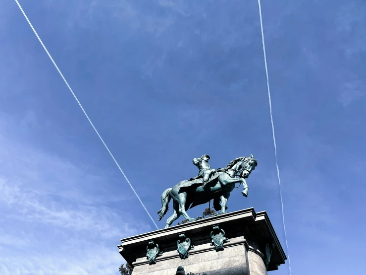 two contrails flying behind the statue of a man