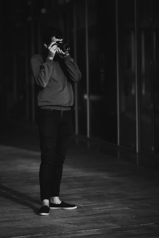 a man standing on a dark street looking at his cell phone