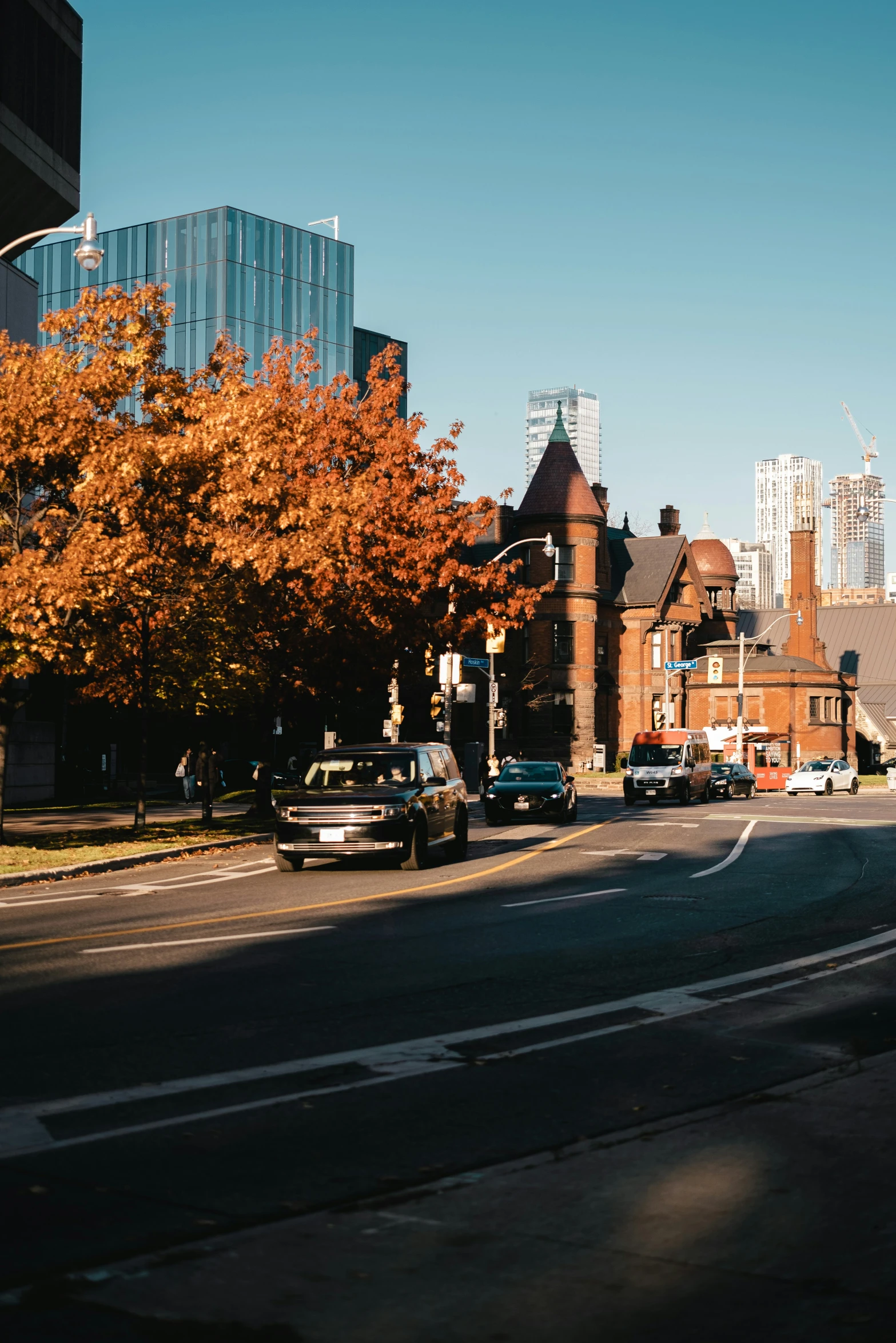 a city street with cars parked and autumn leaves in the trees