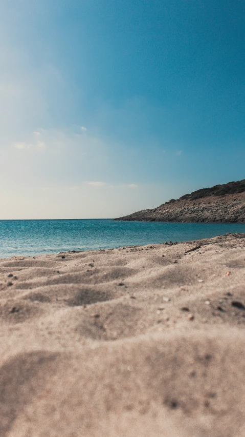 a beach area with a blue ocean and mountains in the background