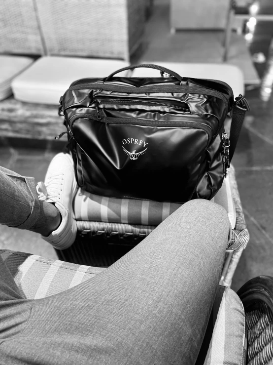 someone's feet resting their arm near a bag of luggage