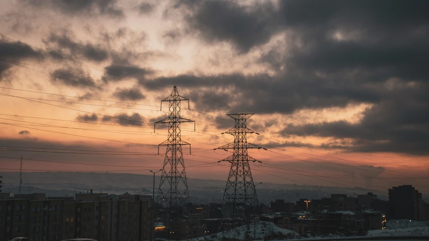 electrical poles and telephone wires in silhouette against a sunset