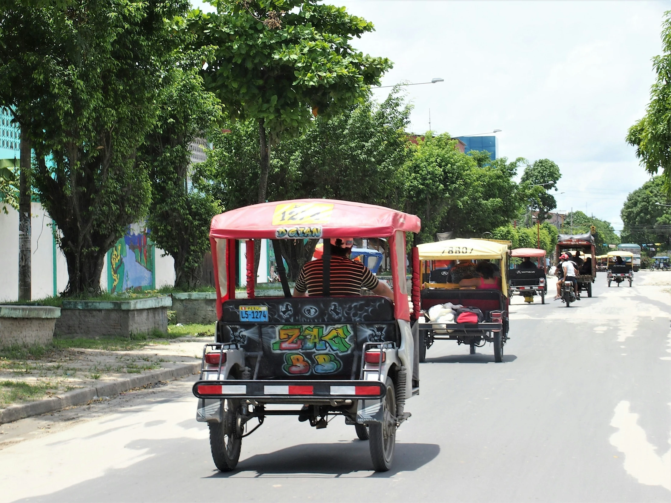 people riding in a four wheeled vehicle down a street