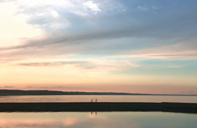 a person sitting on a dock over looking a body of water