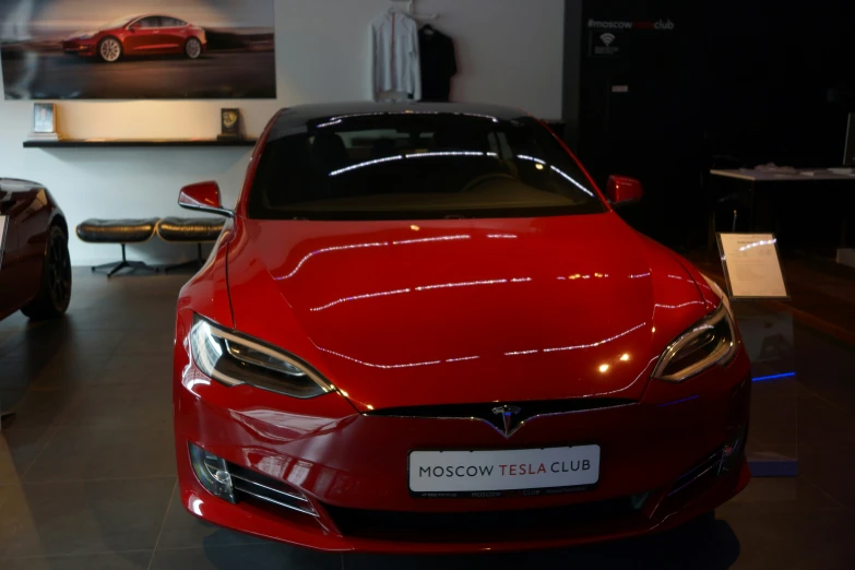 a red tesla car is sitting on the floor