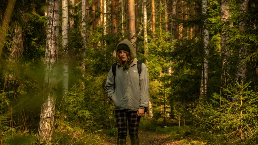 a man stands alone in a forest looking to his left