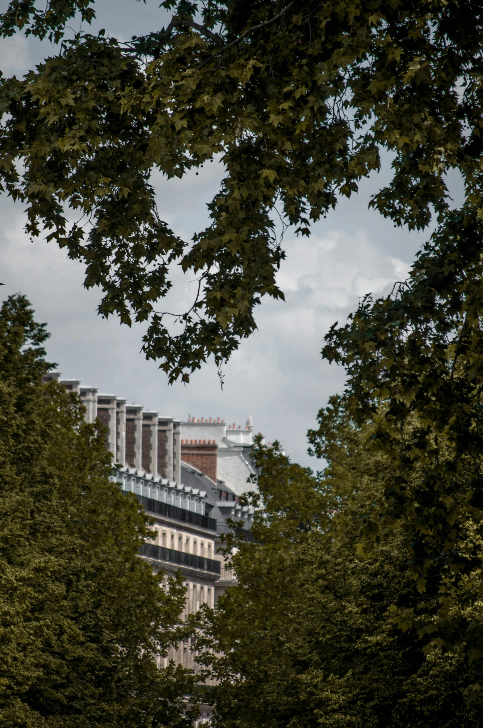 an apartment building surrounded by trees and a cloudy sky