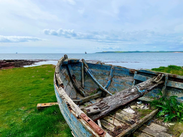 a broken and outbuildinged row boat near a beach