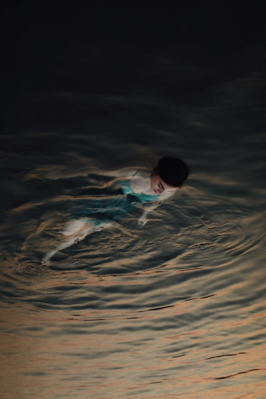 a girl swimming in some dark water at night