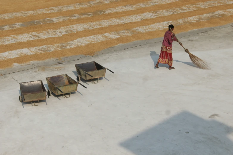 a woman sweeping the pavement with a broom